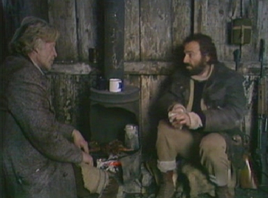 Charles and Fenton dine on rabbit in the wooden hut